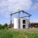 A grassy field with a clearing for a 3D-printing construction rig, with a concrete structure underneath it.