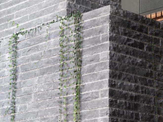 A gray stone structure with green ivy creeping down.