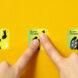 three green stamps against a yellow background. from left to right, the stamps show one figure migrating, then a person pressing their finger to the stamp, and finally the stamp showing many people migrating.