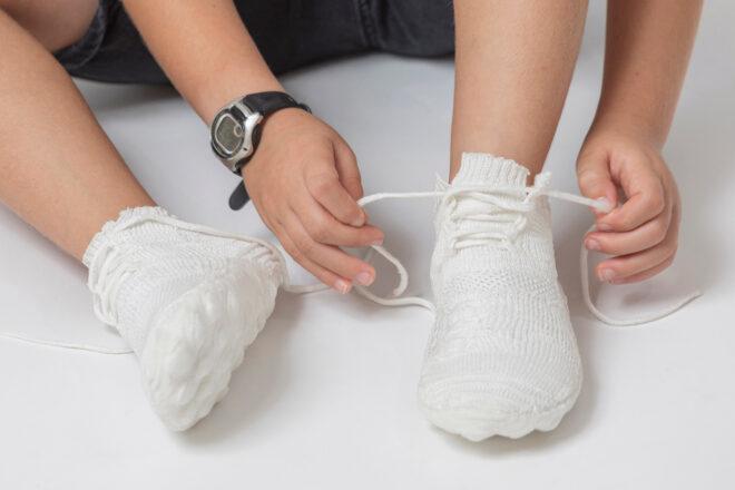person lacing white sneakers
