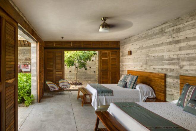 A bedroom with warm wood sliding doors and wood headboards on the two beds.