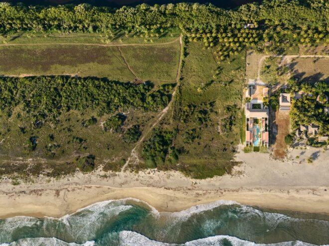 An aerial view of the beach home, coast and surrounding land.