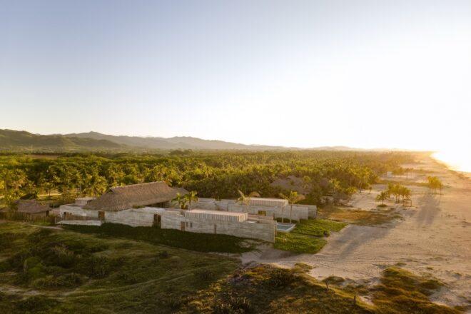 An aerial view of the beach home, coast and surrounding land.