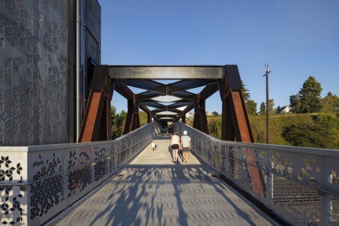 people walking on aluminum and weathered steel bridge