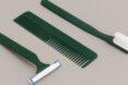 green razor, comb and toothbrush on gray background