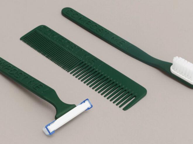 green razor, comb and toothbrush on gray background