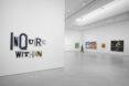 A white gallery space. To the left, a sign that says 