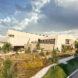rendering of large tan building surrounded by plants and greenery