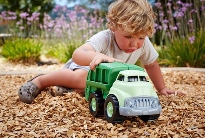 kid playing with green recycling truck toy