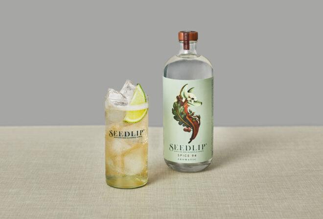 A bottle of Spice 94 by Seedlip next to a cocktail glass.