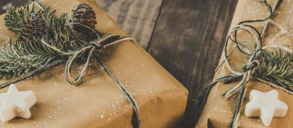 Brown paper packages tied up with string and decorated with white star shapes, pine needles and pinecones.