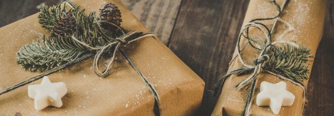 Brown paper packages tied up with string and decorated with white star shapes, pine needles and pinecones.