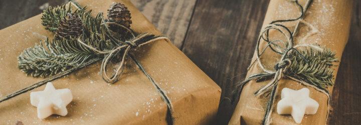 Brown paper packages tied up with string and decorated with white star shapes, pine needles and pinecones.
