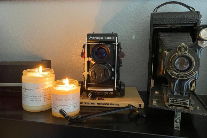 two candles near old cameras on fireplace mantel