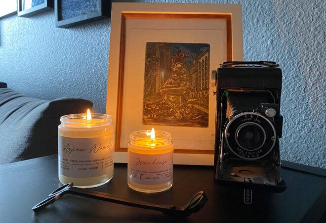 two lit candles near a camera and a drawing