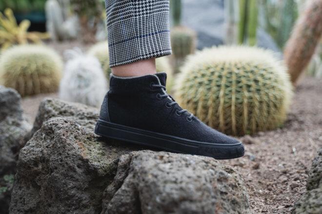 person in black sneakers stepping on a rock