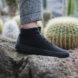 person in black sneakers stepping on a rock
