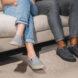 two people in gray sneakers sitting on a couch