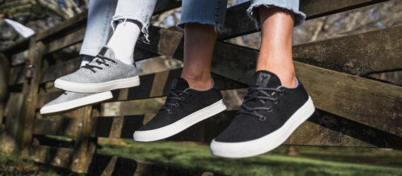 one person in black sneakers and one person in gray sneakers both sitting on a fence