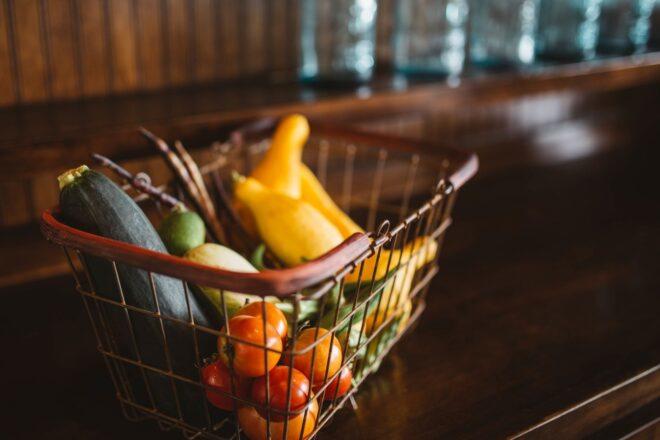 A basket full of produce, including squash and tomatoes.
