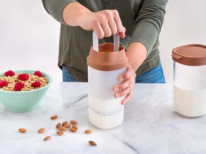 A person using a milk press to make almond milk.