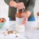 A person using a milk press to make almond milk.
