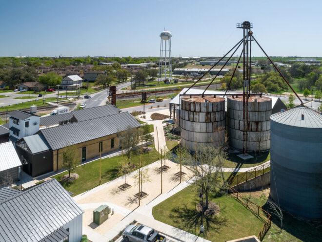 aerial view of property with gabled buildings and rusty silos