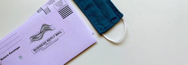 ballot mail envelope next to blue face mask