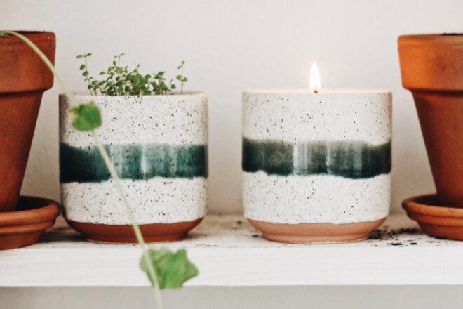 plant in ceramic container next to candle in the same type of ceramic container