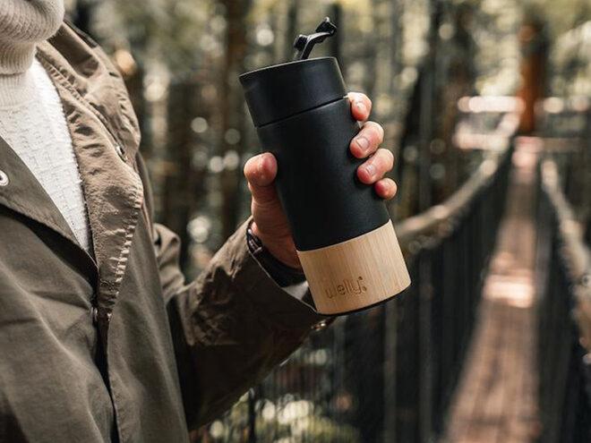 Person holding black reusable coffee cup
