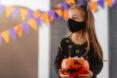 kid wearing mask with painted whiskers and a headband with cat ears