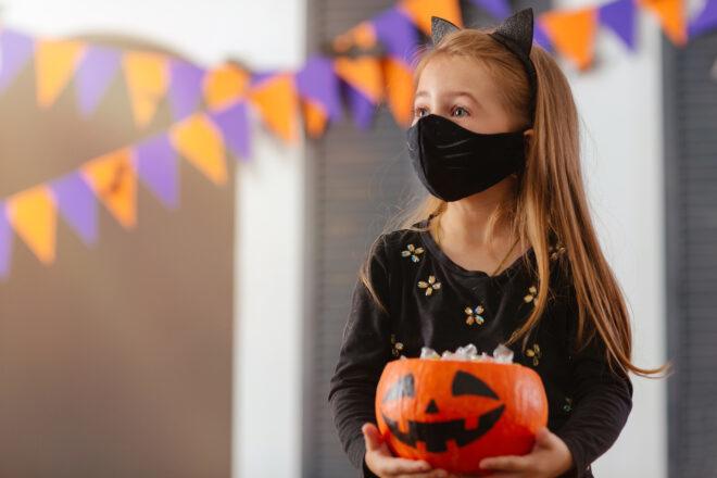 kid wearing mask with painted whiskers and a headband with cat ears