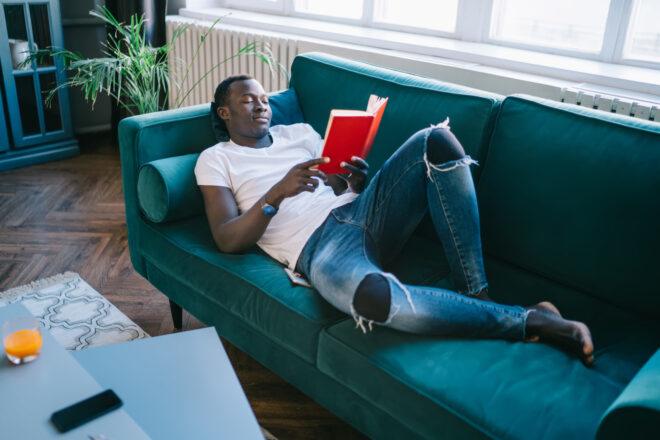 person lounging on couch in ripped jeans