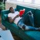 person lounging on couch in ripped jeans