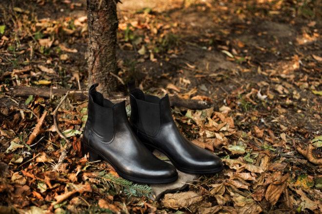 black chelsea boots on pile of fallen leaves