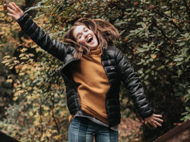 person wearing black Patagonia puffer jacket over an orange sweater