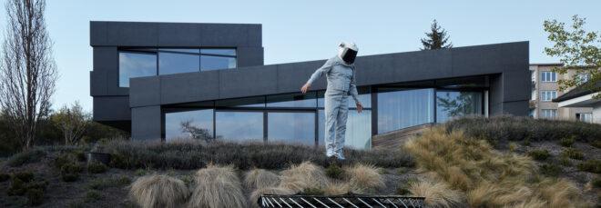 An exterior view of the home, with a person in an astronaut costume bouncing on a trampoline in the front yard.