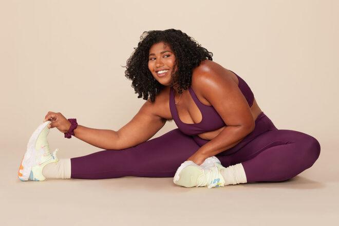 a person sitting and stretching in purple athleticware.