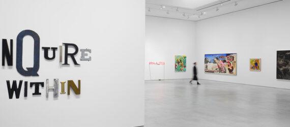 A white gallery space. To the left, a sign that says 
