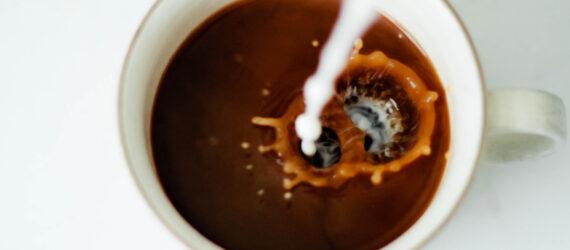 milk pouring into cup of coffee