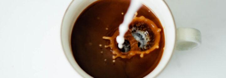 milk pouring into cup of coffee