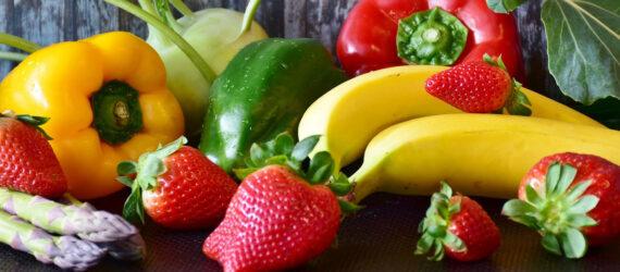 bananas, strawberries, peppers and asparagus on wood background