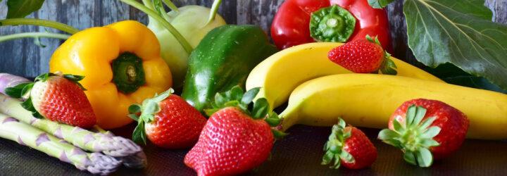 bananas, strawberries, peppers and asparagus on wood background