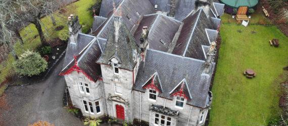 An aerial photo of a 19th century building with grey stone and red accents.