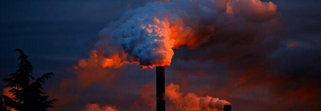 a blue and red photo of a smoke stack emitting pollution