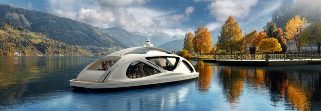 white pod-like ferry on water with autumnal trees and snow-capped mountains in the background