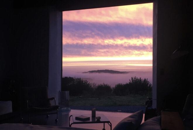 An open doorway showing a pink and purple sunset.