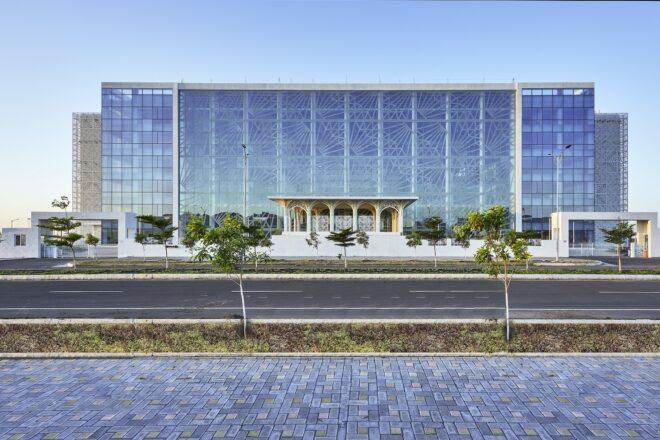 A streetview of a large rectangular building with a glass facade.