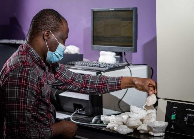 A person in a lab holding a white object in their hand.