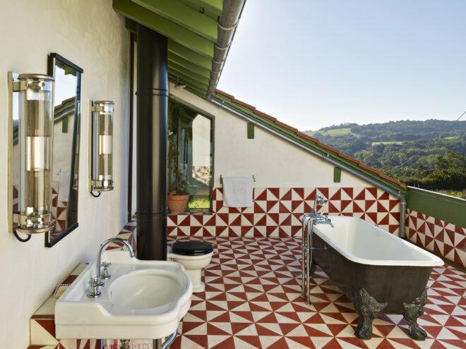 A rooftop bathroom with white and red checkered floor and clawfoot bathtub.